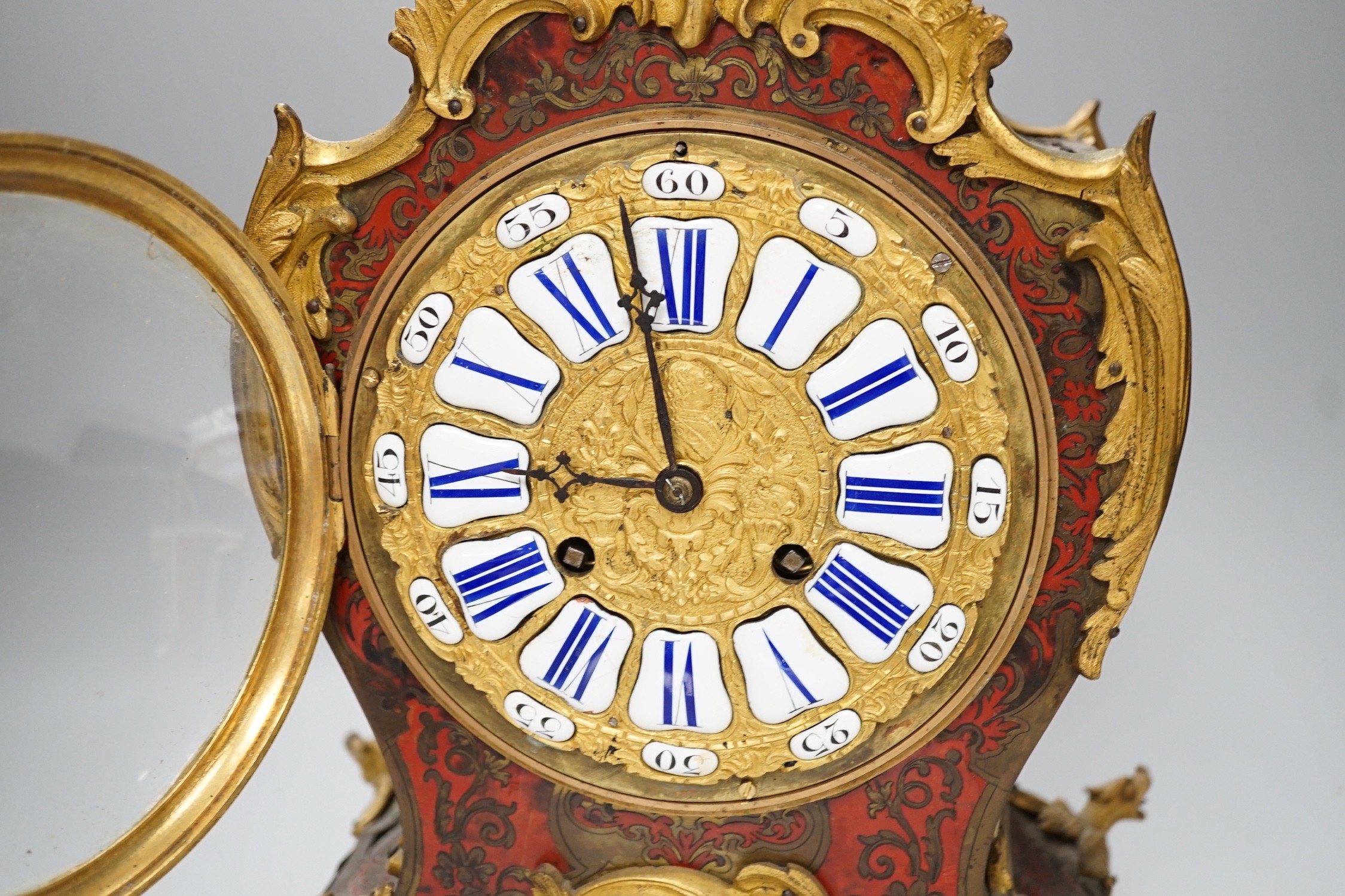 A French scarlet Boulle work and ormolu mounted mantel clock with enamel dial, 45cms high